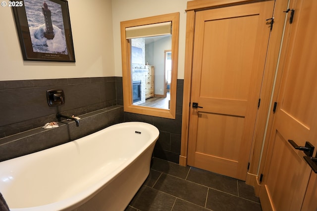 full bath with a wainscoted wall, a soaking tub, tile walls, and tile patterned floors