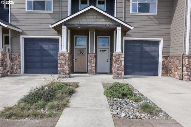 doorway to property featuring a garage, stone siding, and driveway