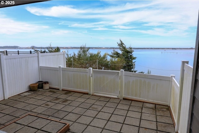 view of patio featuring a water view, fence, and a gate