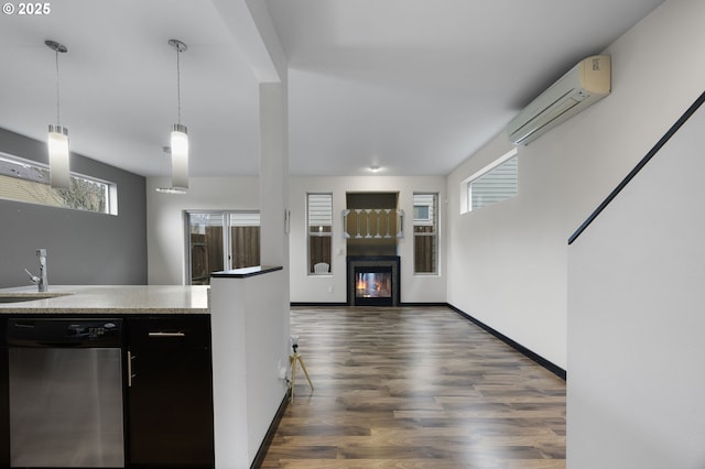 kitchen with dark wood finished floors, decorative light fixtures, a glass covered fireplace, a wall mounted AC, and stainless steel dishwasher