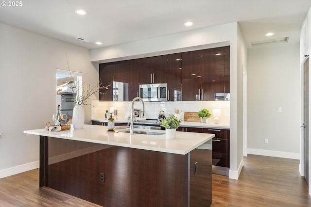 kitchen featuring visible vents, decorative backsplash, dark wood-style floors, modern cabinets, and stainless steel microwave