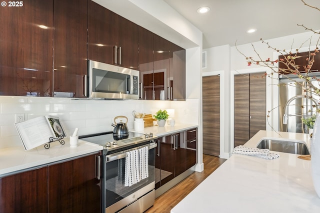 kitchen with wood finished floors, a sink, light countertops, appliances with stainless steel finishes, and modern cabinets