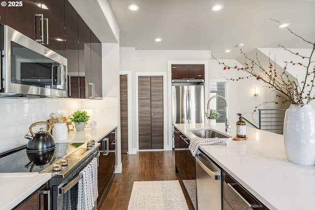 kitchen with dark wood-type flooring, a sink, light countertops, appliances with stainless steel finishes, and modern cabinets