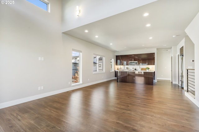 unfurnished living room with baseboards, dark wood finished floors, and recessed lighting