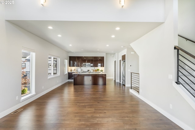 unfurnished living room with dark wood-style flooring, visible vents, and recessed lighting