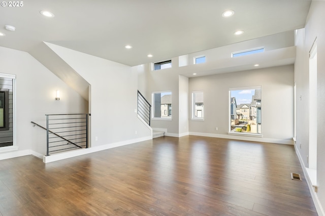 unfurnished living room featuring stairs, visible vents, wood finished floors, and recessed lighting
