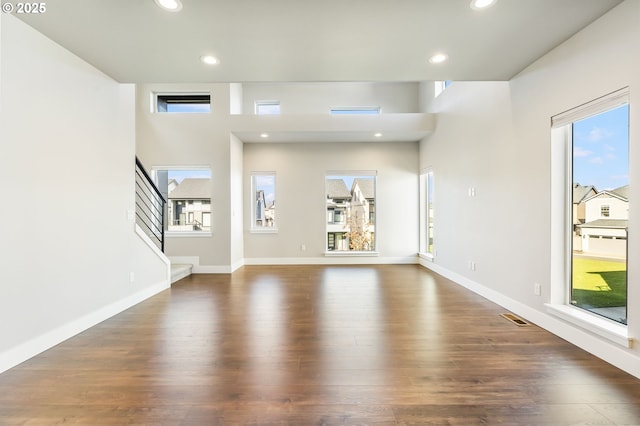 unfurnished living room with dark wood-style flooring, visible vents, and recessed lighting