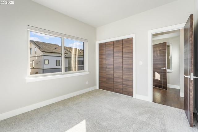 unfurnished bedroom with a closet, baseboards, and carpet flooring