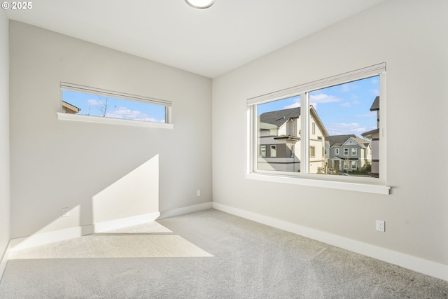 carpeted empty room featuring baseboards