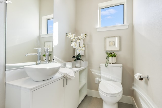 half bathroom featuring baseboards, vanity, and toilet