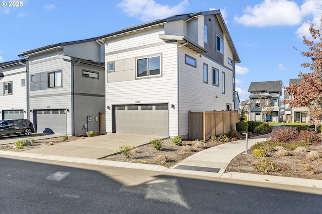 view of front of property with driveway, an attached garage, and fence
