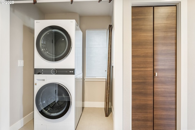 laundry area with stacked washer and clothes dryer, baseboards, and laundry area