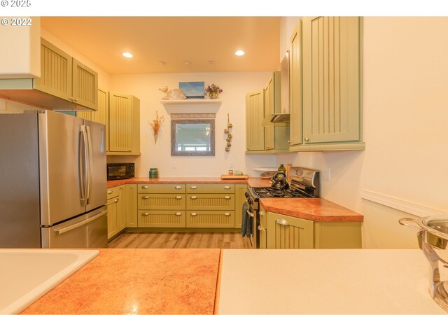 kitchen with stainless steel appliances, light wood-type flooring, and wall chimney exhaust hood