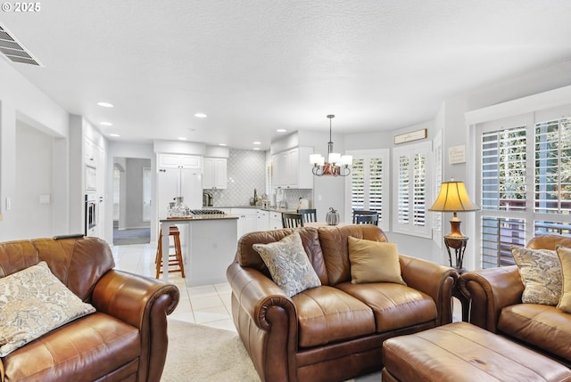 living room with light tile patterned floors, visible vents, an inviting chandelier, a textured ceiling, and recessed lighting