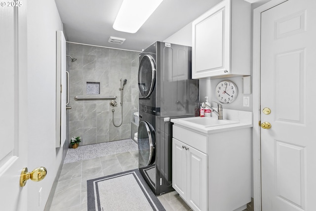 full bath with a tile shower, vanity, and stacked washer / drying machine