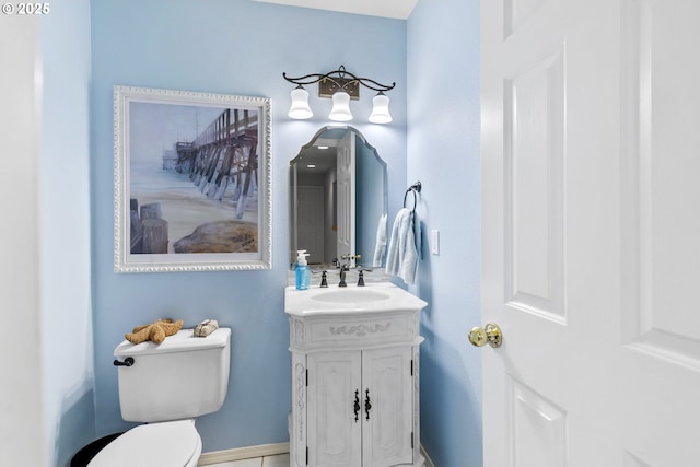 half bath featuring baseboards, vanity, and toilet