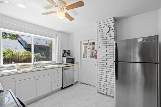 kitchen with appliances with stainless steel finishes, a sink, plenty of natural light, and white cabinetry
