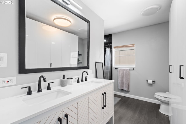 full bathroom featuring wood finished floors, curtained shower, toilet, baseboards, and double vanity