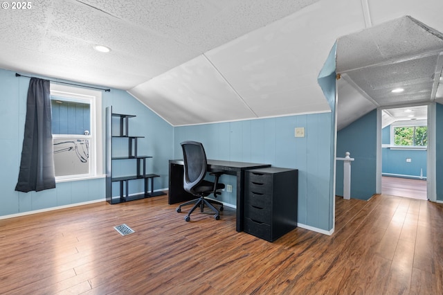office space with wood finished floors, vaulted ceiling, baseboards, and a textured ceiling
