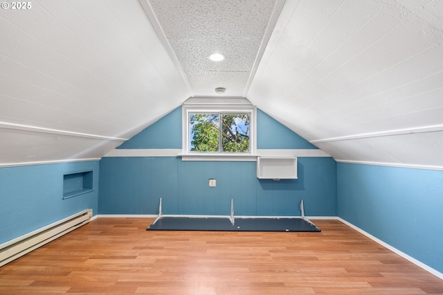 bonus room featuring baseboard heating, wood finished floors, lofted ceiling, and baseboards