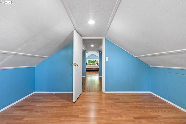 additional living space featuring wood finished floors, baseboards, and vaulted ceiling