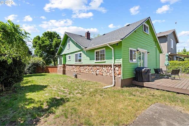 view of side of property featuring a deck, a chimney, a shingled roof, and stone siding