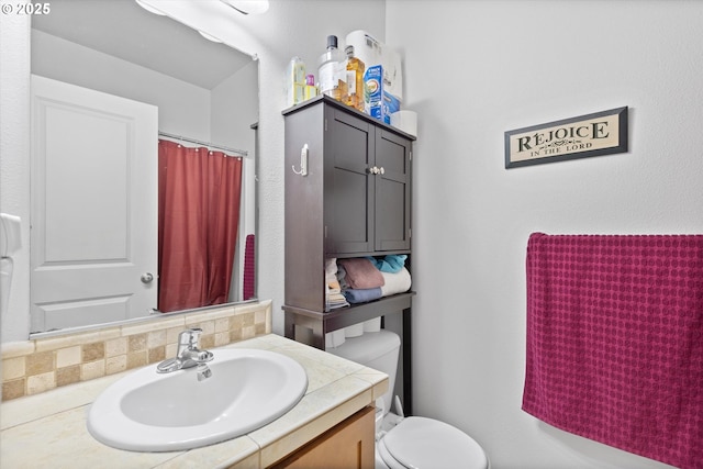 bathroom featuring vanity, backsplash, toilet, and walk in shower