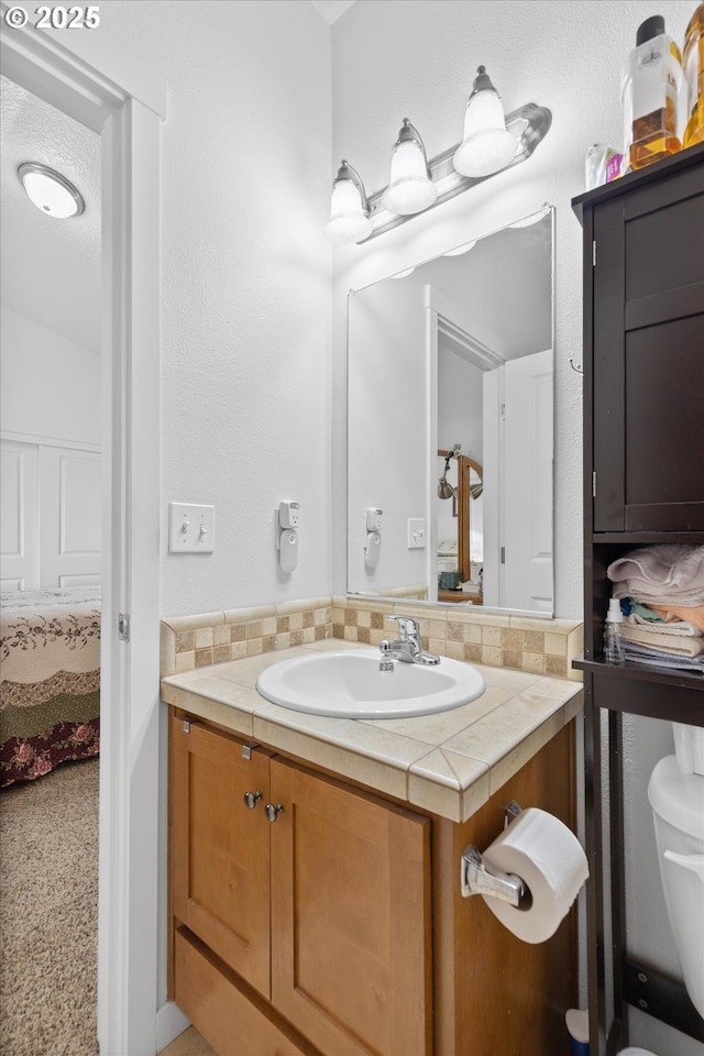 bathroom with vanity, backsplash, and toilet