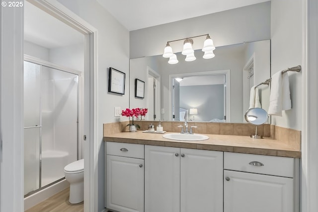 bathroom with hardwood / wood-style flooring, vanity, an enclosed shower, and toilet