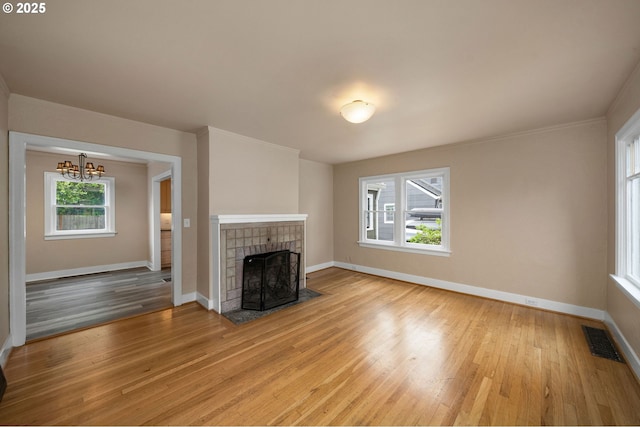 7817 SE Ellis St, Portland, OR 97206 - unfurnished living room featuring a chandelier, light wood-style flooring, baseboards, and a tiled fireplace