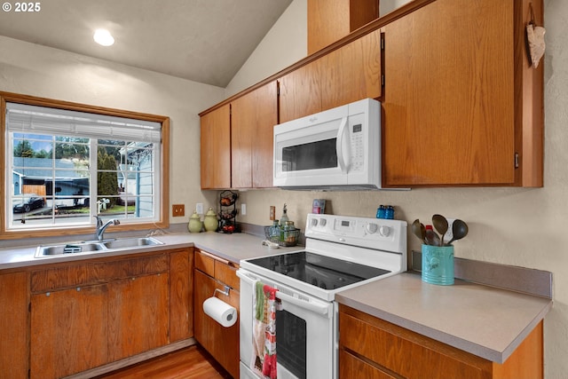 kitchen with brown cabinets, white appliances, light countertops, and a sink