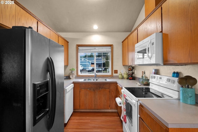 kitchen with white appliances, a sink, light wood-style floors, light countertops, and brown cabinets