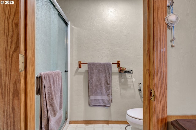 bathroom with a shower with door, a textured wall, toilet, and tile patterned floors