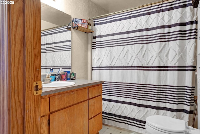 full bath with toilet, a textured wall, vanity, and tile patterned floors