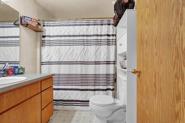 bathroom featuring toilet, a textured wall, vanity, and tile patterned floors