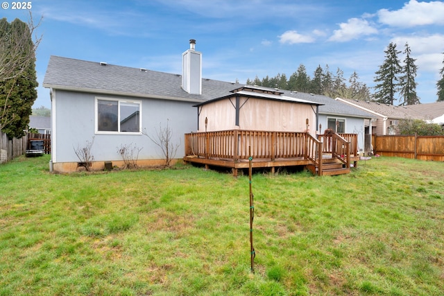 rear view of house featuring a lawn, a chimney, roof with shingles, fence, and a deck