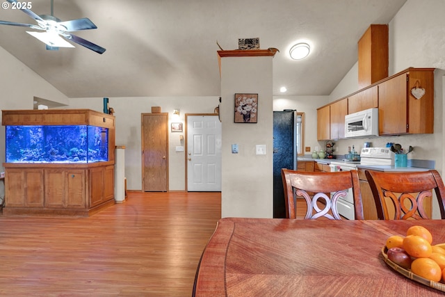 kitchen featuring light wood-style flooring, brown cabinetry, vaulted ceiling, ceiling fan, and white appliances