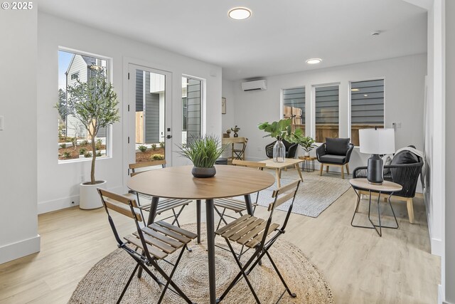 dining space with light hardwood / wood-style flooring and an AC wall unit