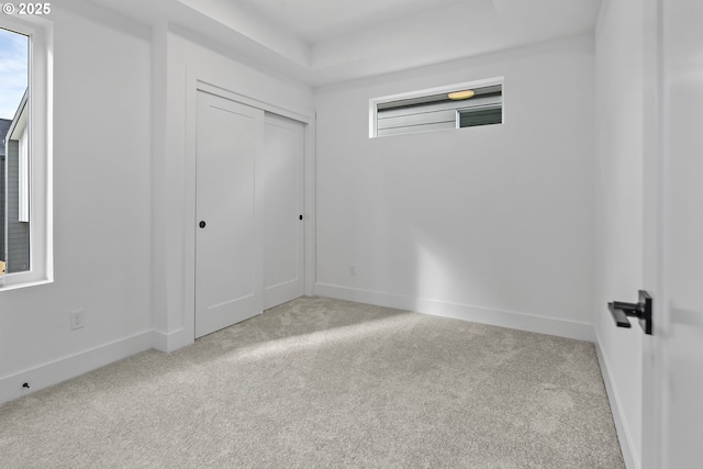 unfurnished bedroom with multiple windows, light colored carpet, and a closet