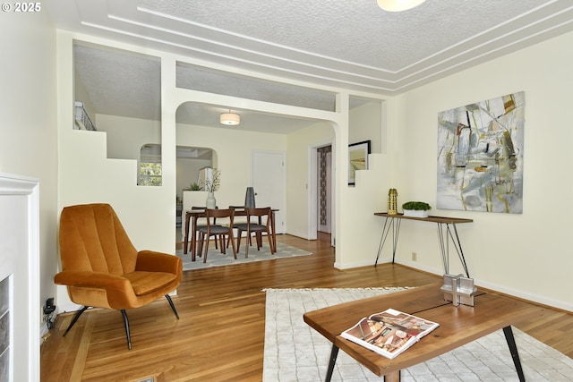 3334 NE 16th Ave, Portland, OR 97212 - living room featuring arched walkways, wood finished floors, a textured ceiling, and baseboards