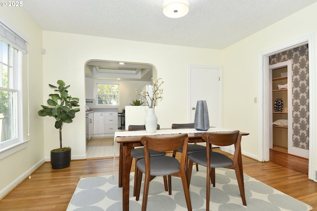 3334 NE 16th Ave, Portland, OR 97212 - dining space with light wood-style flooring, baseboards, a textured ceiling, and arched walkways