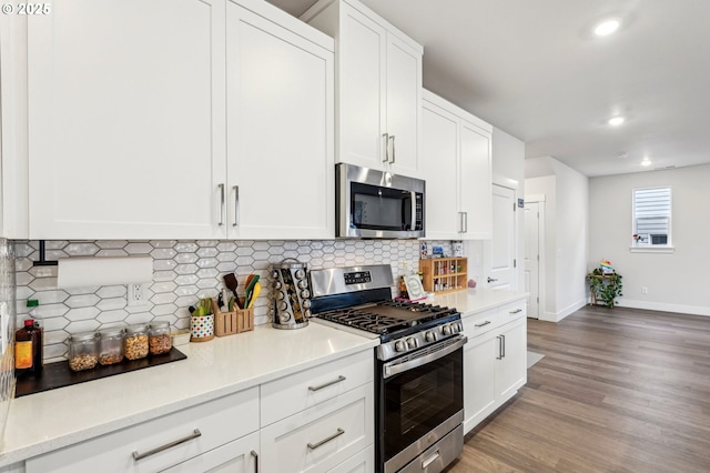 kitchen featuring stainless steel appliances, white cabinetry, decorative backsplash, and light hardwood / wood-style flooring