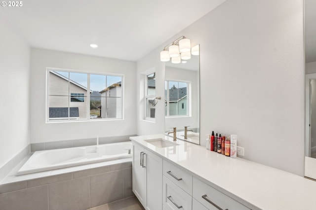 bathroom featuring tiled tub, vanity, and a healthy amount of sunlight