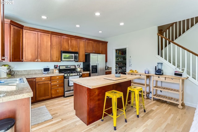 9288 SW Diamond View Way, Beaverton, OR 97007 - kitchen with stainless steel appliances, light wood finished floors, a kitchen bar, recessed lighting, and a center island