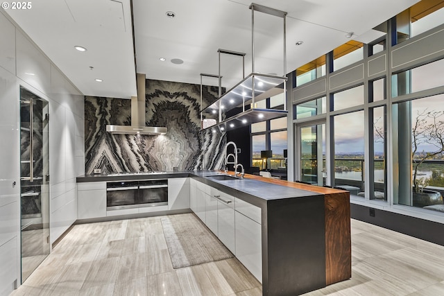 3601 S River Pkwy Unit 3101, Portland, OR 97239 - kitchen with stainless steel oven, modern cabinets, a sink, wall chimney exhaust hood, and recessed lighting