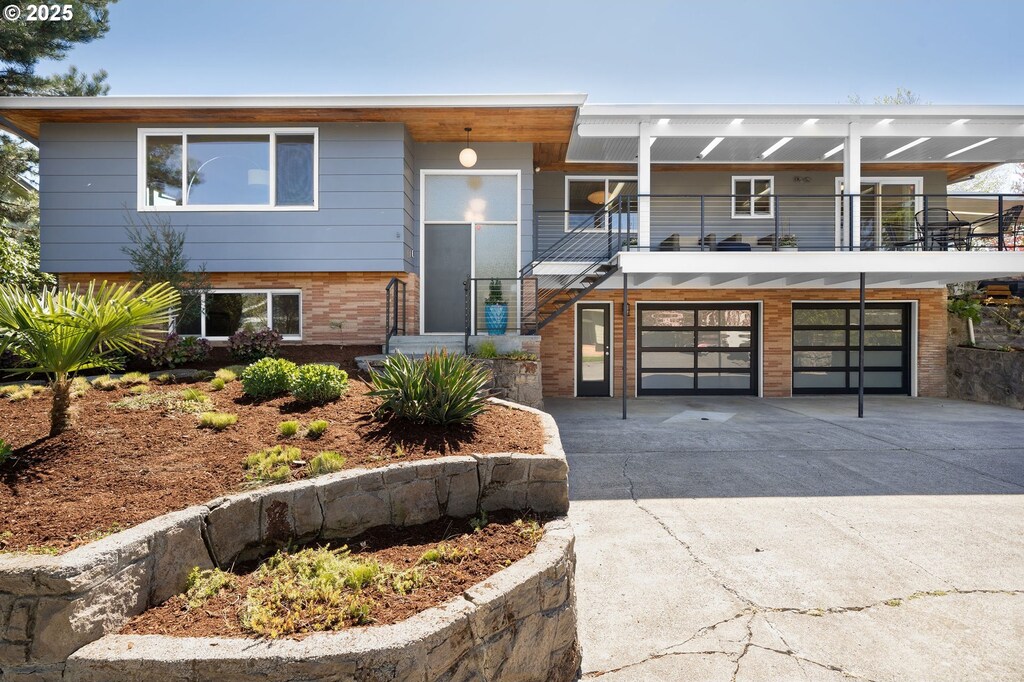 view of front of home featuring an attached garage, brick siding, a balcony, and driveway