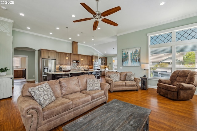 living area with arched walkways, crown molding, ceiling fan, recessed lighting, and wood finished floors