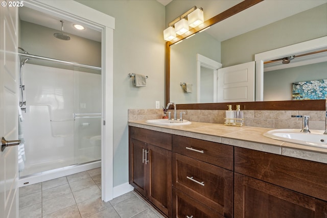 bathroom featuring a stall shower, double vanity, and tile patterned flooring