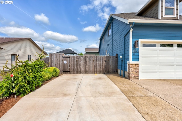 view of side of property featuring a gate, a garage, fence, and concrete driveway