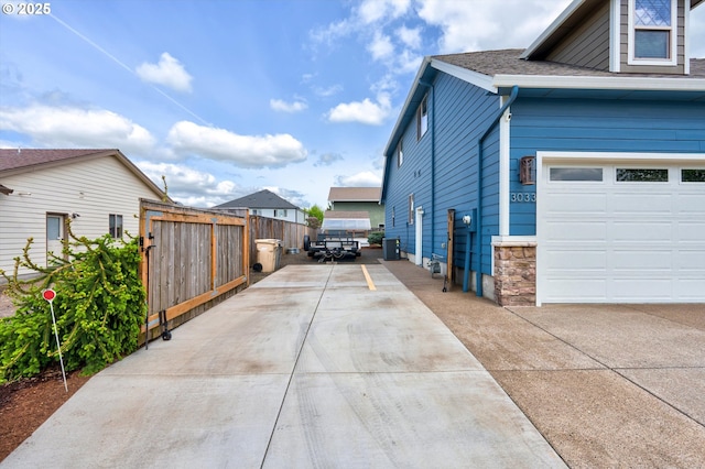 view of side of home with driveway, fence, roof with shingles, and cooling unit